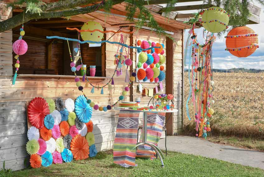 Eine Boho Sommerhochzeit lässt sich mit Wabenbällen. Lampions und Pompoms wunderbar für draußen dekorieren