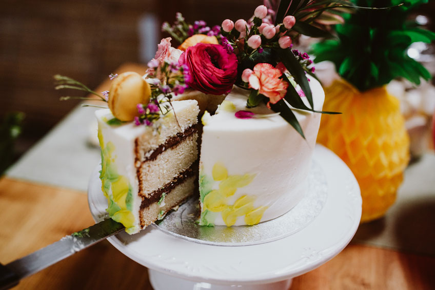 Tropisch verzierter Kuchen mit Pflanzen und Macarons